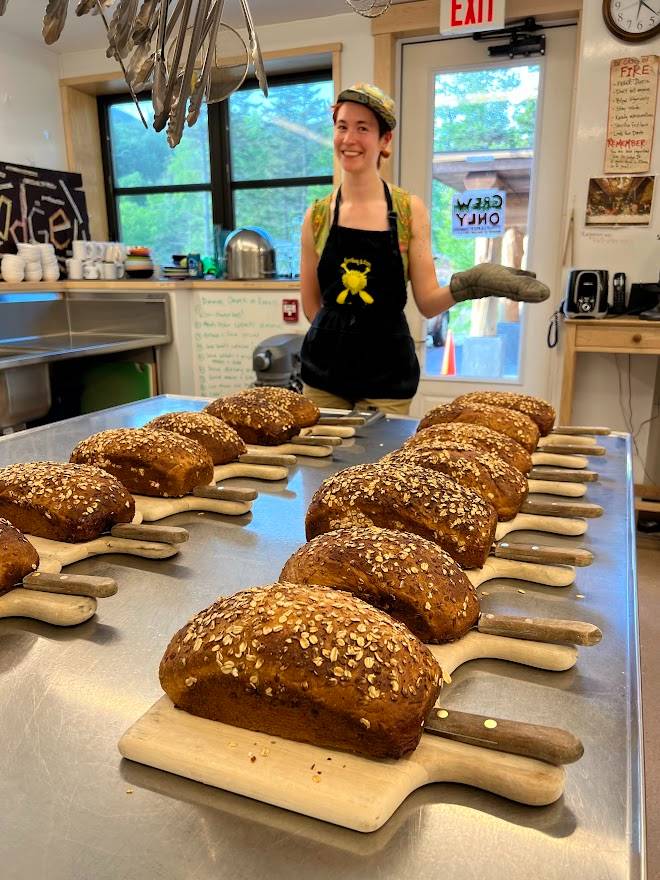 In the front, many loaves of bread sit on cutting boards, ready to be served to Lodge guests. A crewling smiles behind them. 