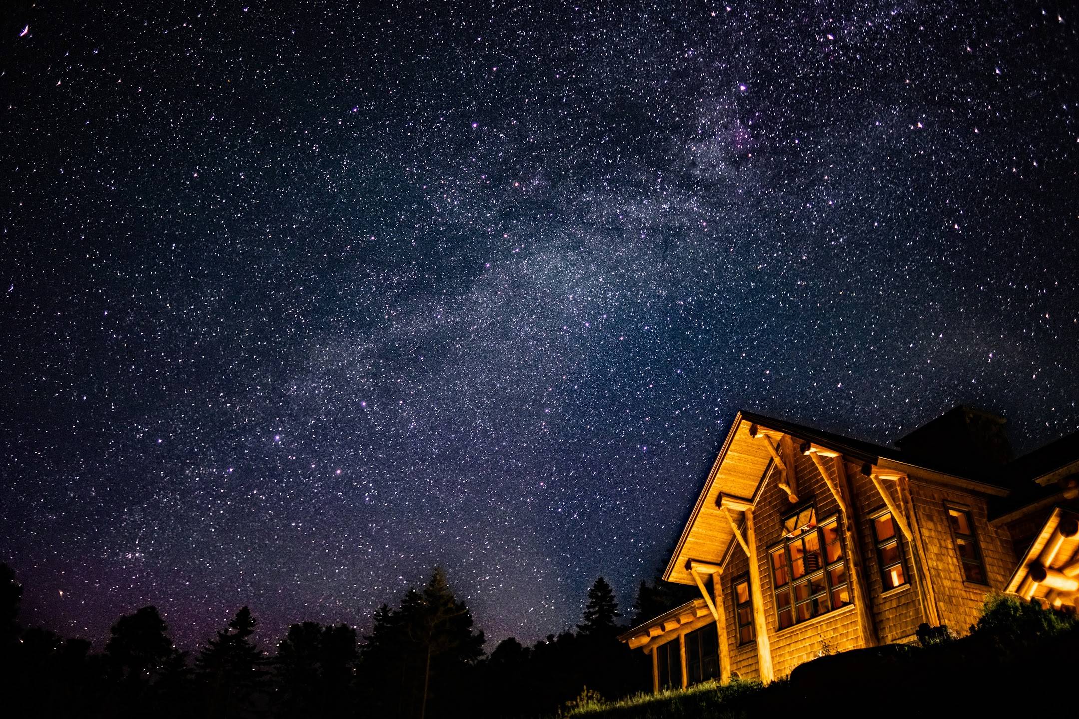 The Lodge glows a warm yellow while the sky is a deep blue and filled with stars.