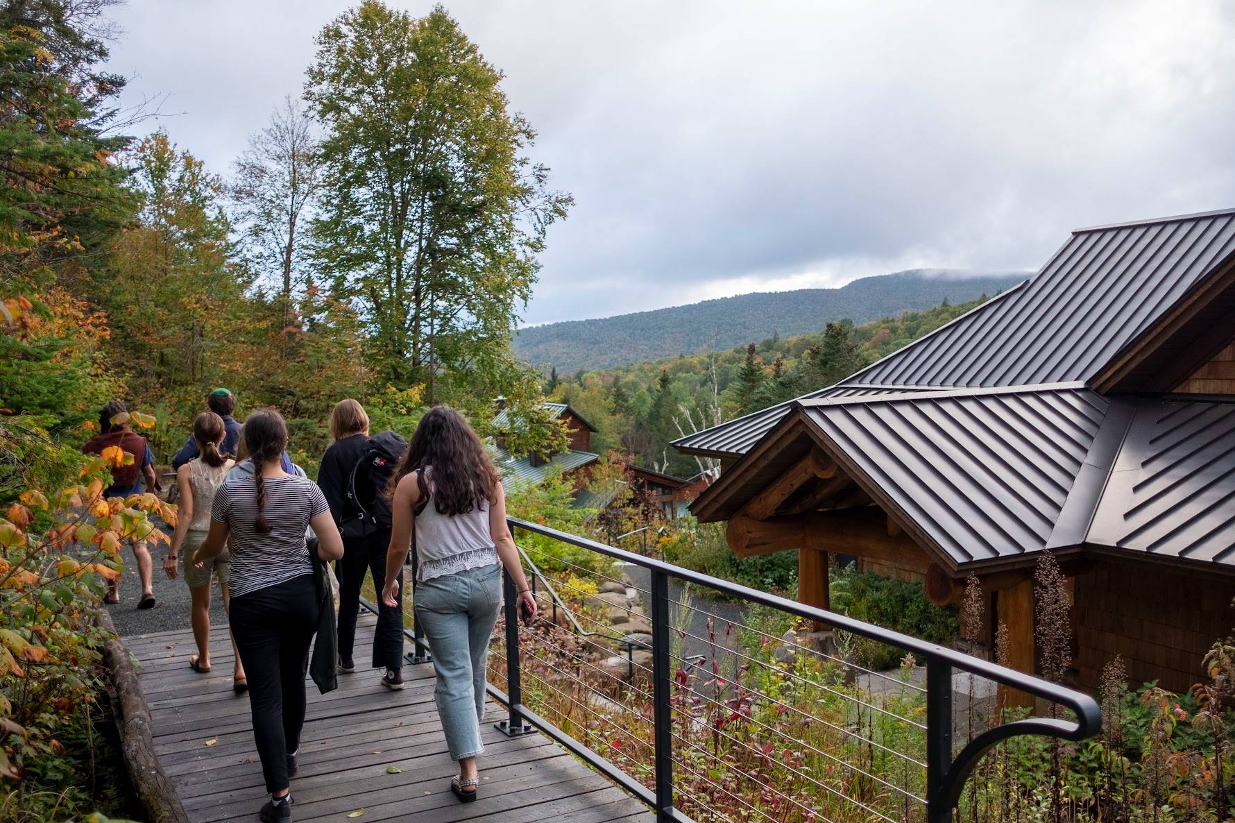Students walk down the path to the Lodge. The plants are lush and the mountain ridge is in the distance.